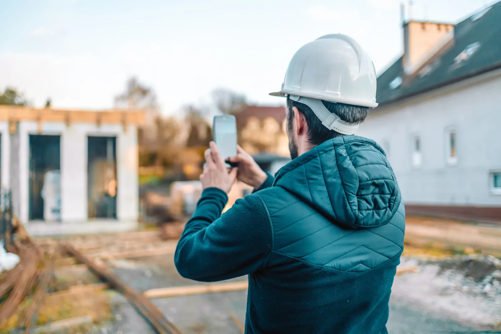 Contractor on a job site taking pictures of the project with his phone.