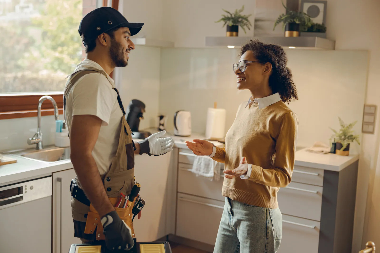 Handyman and happy client standing and discussing in a kitchen.